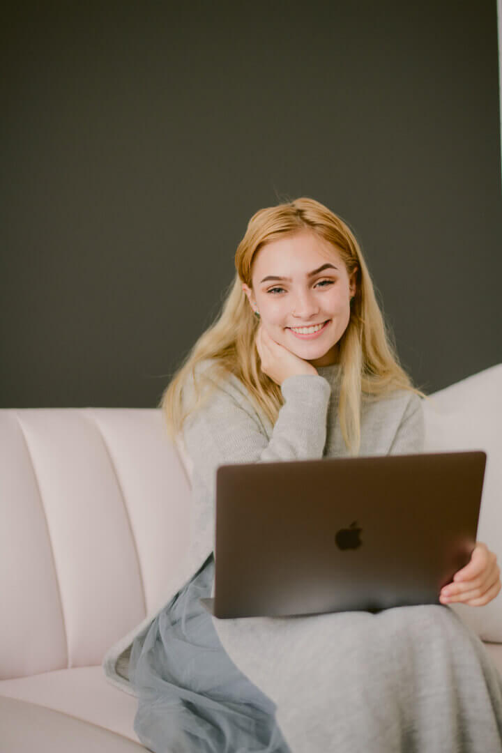A girl smiling with a laptop on her lap